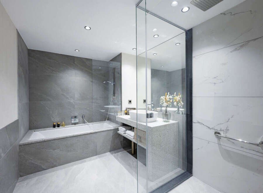 This luxurious bathroom boasts a spacious bathtub, a modern vanity with ample storage, and elegant marble tiling.