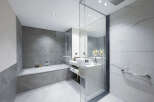 This luxurious bathroom boasts a spacious bathtub, a modern vanity with ample storage, and elegant marble tiling.