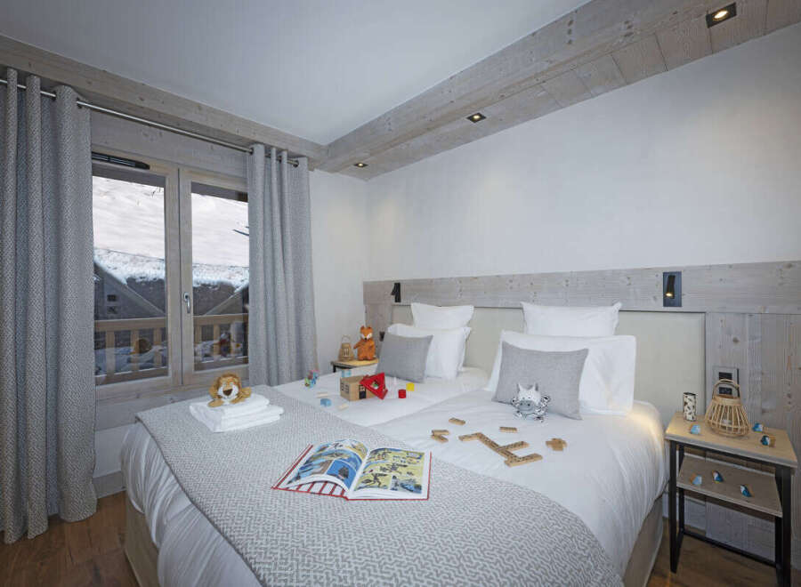 Cozy bedroom with twin beds, featuring a rustic wooden headboard and gray bedding.