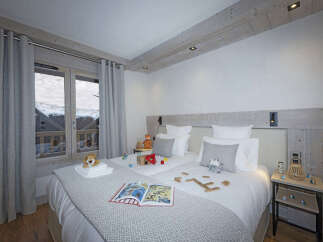 Cozy bedroom with twin beds, featuring a rustic wooden headboard and gray bedding.