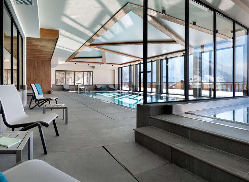 Luxury hotel indoor pool and relaxation area with large windows offering stunning mountain views.