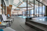 Luxury hotel indoor pool and relaxation area with large windows offering stunning mountain views.