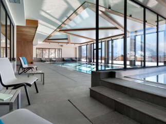 Luxury hotel indoor pool and relaxation area with large windows offering stunning mountain views.