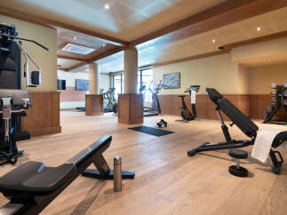 This stunning gym boasts state-of-the-art equipment, including treadmills, ellipticals, stationary bikes, and weight machines, all set against a backdrop of rich wood paneling and a light-filled space.