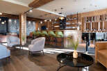 This stunning hotel lobby boasts a chic bar with green velvet stools, a grand piano, and comfortable seating areas.