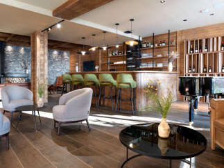 This stunning hotel lobby boasts a chic bar with green velvet stools, a grand piano, and comfortable seating areas.