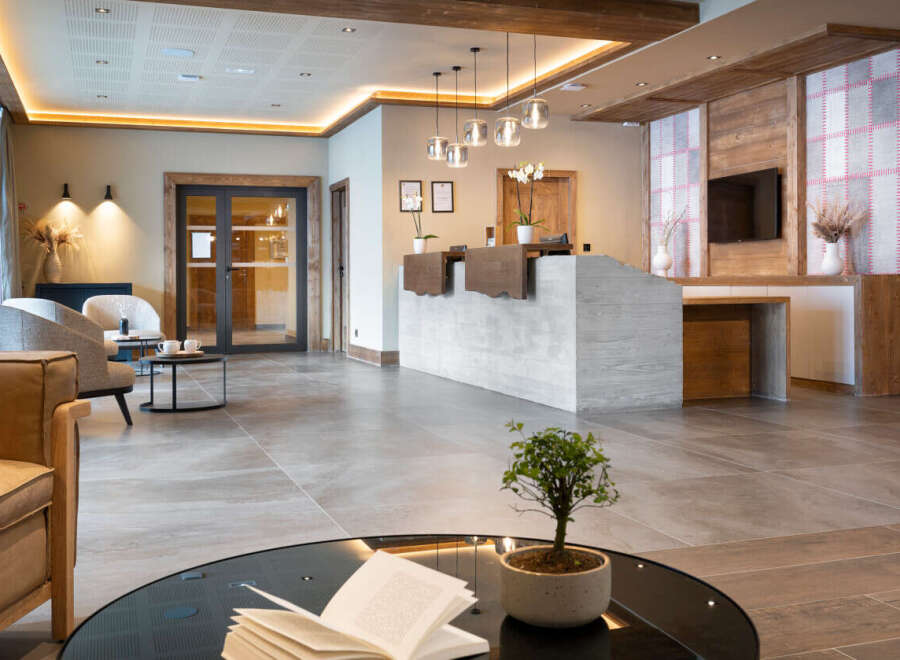 This hotel boasts a spacious lobby with a modern concrete reception desk, complemented by warm wooden accents and stylish pendant lighting.