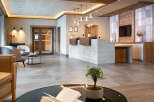 This hotel boasts a spacious lobby with a modern concrete reception desk, complemented by warm wooden accents and stylish pendant lighting.