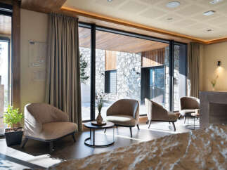 This stunning hotel lobby boasts floor-to-ceiling windows showcasing breathtaking mountain views, creating a bright and airy atmosphere.