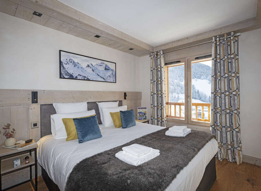 This stunning bedroom boasts a cozy king-size bed dressed in plush linens and a faux fur throw, perfect for relaxing after a day on the slopes.