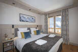 This stunning bedroom boasts a cozy king-size bed dressed in plush linens and a faux fur throw, perfect for relaxing after a day on the slopes.