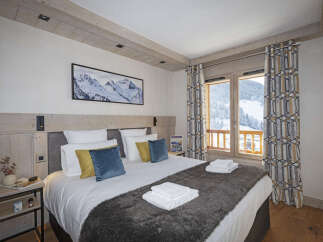 This stunning bedroom boasts a cozy king-size bed dressed in plush linens and a faux fur throw, perfect for relaxing after a day on the slopes.