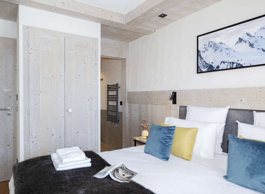 This stunning bedroom boasts a cozy and luxurious atmosphere, featuring a plush bed with soft pillows and a warm, textured throw.