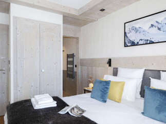 This stunning bedroom boasts a cozy and luxurious atmosphere, featuring a plush bed with soft pillows and a warm, textured throw.