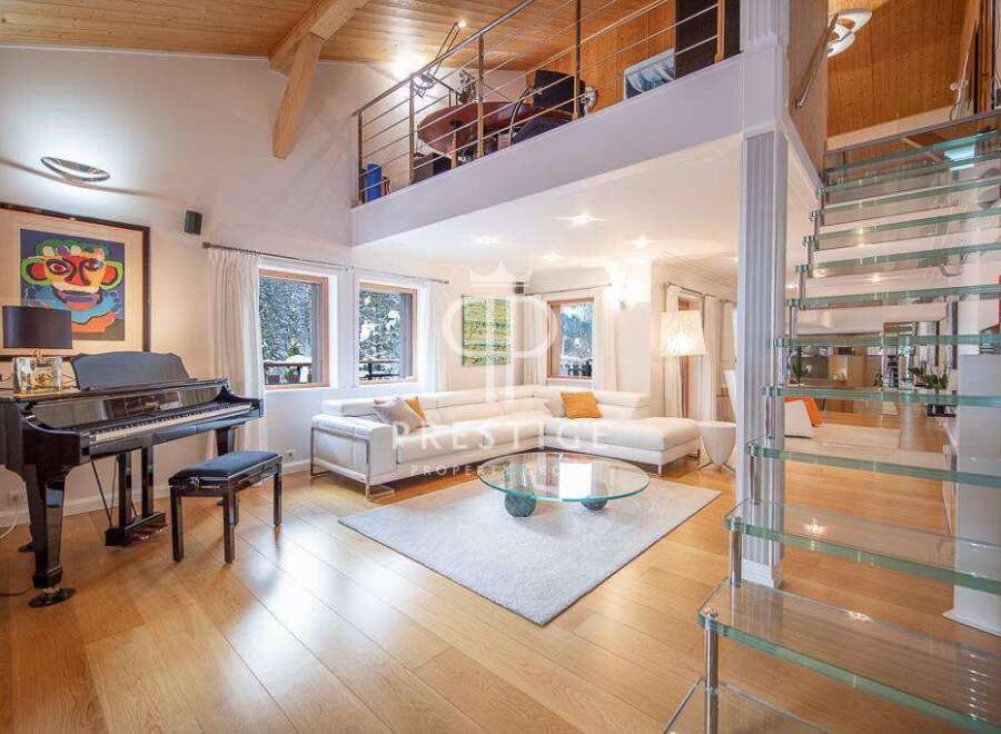 Experience luxury living in this stunning property featuring a grand piano and a modern glass staircase.