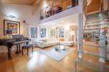 Experience luxury living in this stunning property featuring a grand piano and a modern glass staircase.