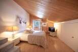 Discover the charm of this cozy bedroom, featuring a unique wooden ceiling and walls that create a warm and inviting atmosphere.