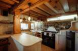 Discover rustic charm in this stunning kitchen! Featuring exposed wooden beams, a stone accent wall, and unique light fixtures, this space exudes warmth and character.