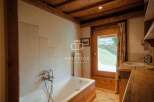 Discover the charm of this property, featuring a cozy bathroom with a wooden bathtub and a rustic wooden ceiling.