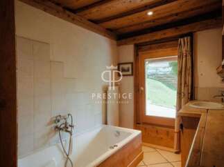 Discover the charm of this property, featuring a cozy bathroom with a wooden bathtub and a rustic wooden ceiling.