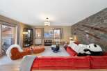 Experience luxury living in this stunning property, featuring a cozy living room with a plush red sofa and a unique panda bear accent.