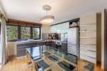 Discover a stunning kitchen with a modern design, featuring a sleek glass dining table and stylish chairs.