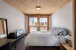 Cozy bedroom with a wooden ceiling and a large window offering natural light.