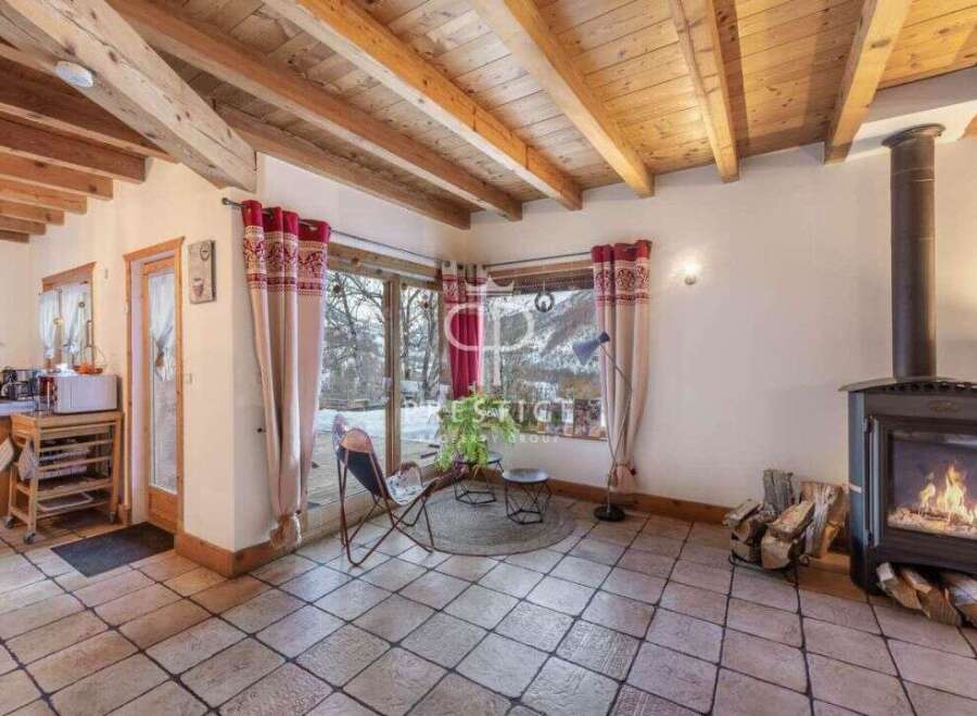 Experience cozy living in this charming chalet, featuring a warm fireplace and exposed wooden beams.