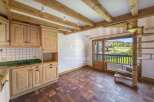 Discover a charming property with a rustic kitchen featuring wooden cabinets and a tiled backsplash.