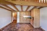 Discover the charm of this rustic kitchen, featuring exposed wooden beams and cabinetry.