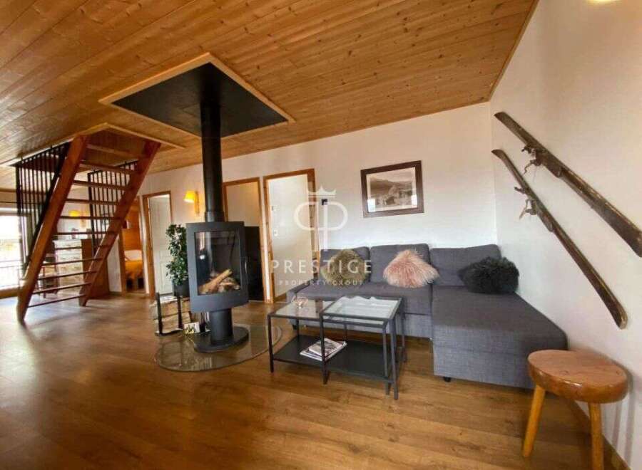 Discover the charm of this cozy living space, featuring a stunning fireplace and a unique wooden staircase.
