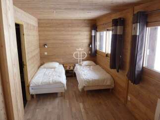 Cozy bedroom with wooden walls and floors, creating a warm and inviting atmosphere.
