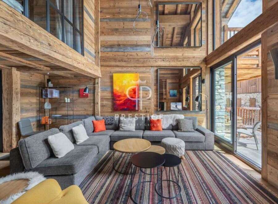 Experience luxury living in this stunning chalet, featuring a spacious living area with a cozy fireplace and large windows.