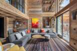 Experience luxury living in this stunning chalet, featuring a spacious living area with a cozy fireplace and large windows.