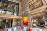 Experience luxury living in this stunning chalet, featuring a warm and inviting interior with exposed wooden beams.