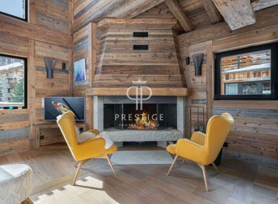 Experience luxury living in this stunning chalet, featuring a cozy fireplace and elegant yellow armchairs.