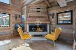 Experience luxury living in this stunning chalet, featuring a cozy fireplace and elegant yellow armchairs.