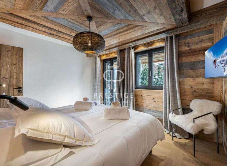 Experience luxury in this stunning bedroom featuring a rustic wooden ceiling and walls, creating a warm and inviting atmosphere.