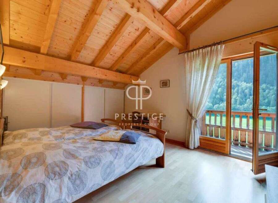 Discover a cozy bedroom with a stunning wooden ceiling and a balcony offering breathtaking views.
