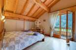 Discover a cozy bedroom with a stunning wooden ceiling and a balcony offering breathtaking views.