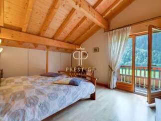 Discover a cozy bedroom with a stunning wooden ceiling and a balcony offering breathtaking views.