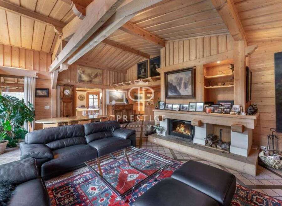 Experience the warmth of this stunning wooden interior, featuring a cozy fireplace and a luxurious black leather sofa.