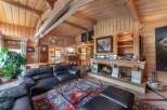 Experience the warmth of this stunning wooden interior, featuring a cozy fireplace and a luxurious black leather sofa.