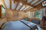 Experience the charm of this cozy bedroom, featuring warm wooden paneling and a rustic aesthetic.