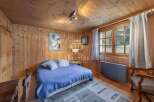 Cozy bedroom with wooden walls and ceiling, creating a warm and inviting atmosphere.