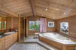 This luxurious bathroom boasts a warm, inviting ambiance with its wooden paneling and vaulted ceiling.