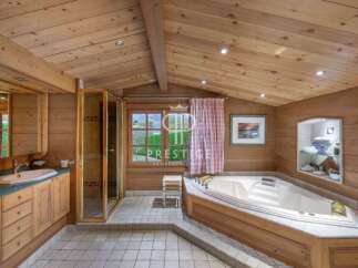 This luxurious bathroom boasts a warm, inviting ambiance with its wooden paneling and vaulted ceiling.