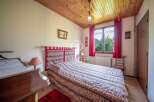 Cozy bedroom with a rustic wooden ceiling and a comfortable bed.