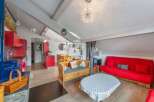 Discover this charming property featuring a cozy living space with a vibrant red sofa and a unique wooden bench.