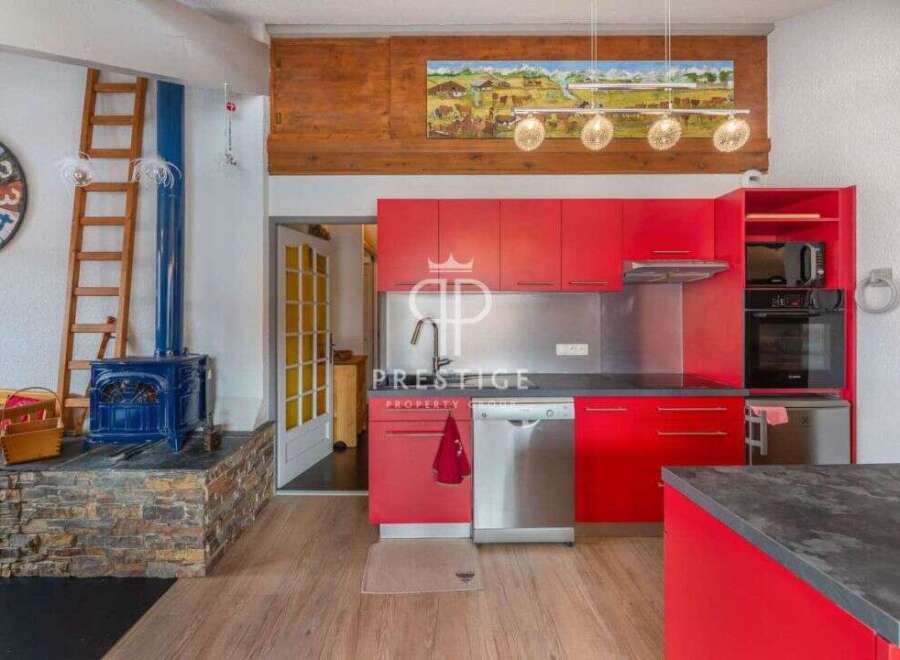 This stunning property boasts a modern kitchen with vibrant red cabinetry, stainless steel appliances, and a sleek countertop.